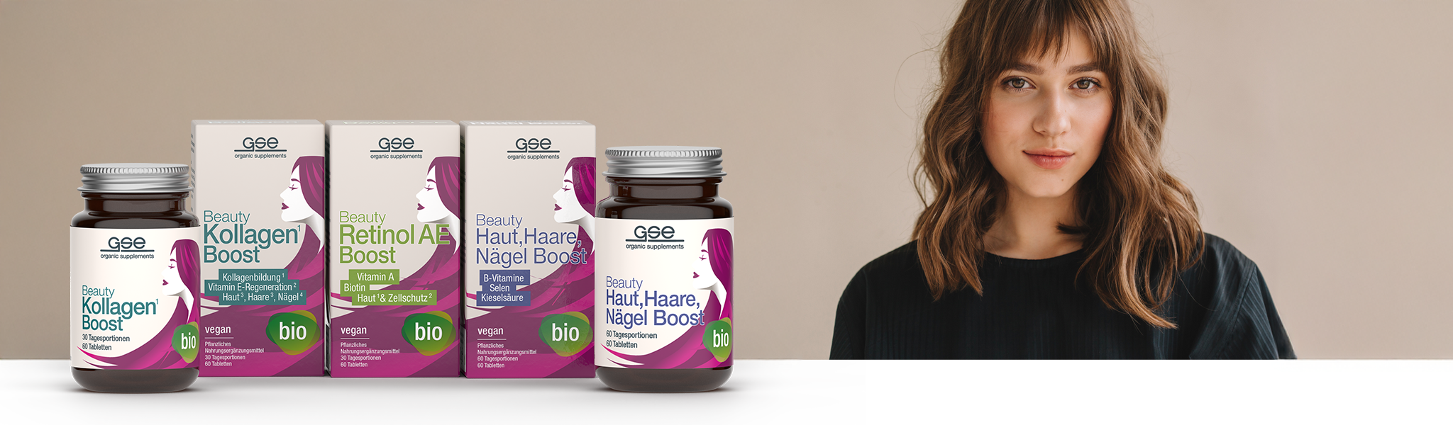 Eine Frau mit schulterlangem braunem Haar steht vor einem neutralen Hintergrund neben einer Ausstellung mit Schönheitspräparaten von GSE, darunter Kollagen Boost, Retinol A Boost und Haut, Haare, Nägel Boost.