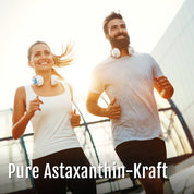 Ein lächelnder Mann und eine lächelnde Frau mit Kopfhörern um den Hals, die gemeinsam im Freien joggen; unten ist der Text Astaxanthin-Oleoresin-Kapseln (Bio) eingeblendet.