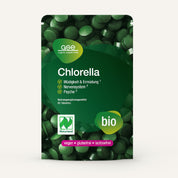 Eine grüne Packung von Naturland Bio Chlorella (Tabletten) von gse.organic.supplements. Die Vorderseite zeigt die deutschen Vorteile, vegane und biologische Etiketten, Informationen über Vitamin B12 und 60 Tabletten. Im Hintergrund sind leuchtend grüne Chlorella-Tabletten zu sehen.