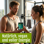 Ein Mann und eine Frau in Sportkleidung stehen in einem Fitnessstudio; der Mann reicht ihr eine Flasche „Naturland Bio Spirulina (Tabletten)“ von gse.organic.supplements. Unten steht: „Natürlich, vegan und voller Energie – das vegane Nahrungsergänzungsmittel mit Eisen.“.