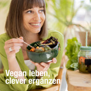 Eine lächelnde Frau im grünen Hemd genießt veganes Essen an einem Tisch mit einem Salatglas und dem Vegan Life Paket von gse organic supplements. "Vegan leben, clever ergänzen." Pflanzen und helle Dekoration unterstreichen die vegane Ernährung.