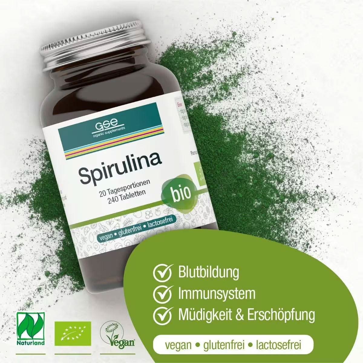 Eine Flasche Naturland Bio Spirulina (Tabletten) von gse.organic.supplements steht auf einem weißen Untergrund mit grünem Spirulina-Pulver. Symbole heben die Vorteile für Blut (Eisen), Immununterstützung und Müdigkeitslinderung hervor. Die Etiketten zeigen, dass das Produkt vegan, gluten- und laktosefrei ist.