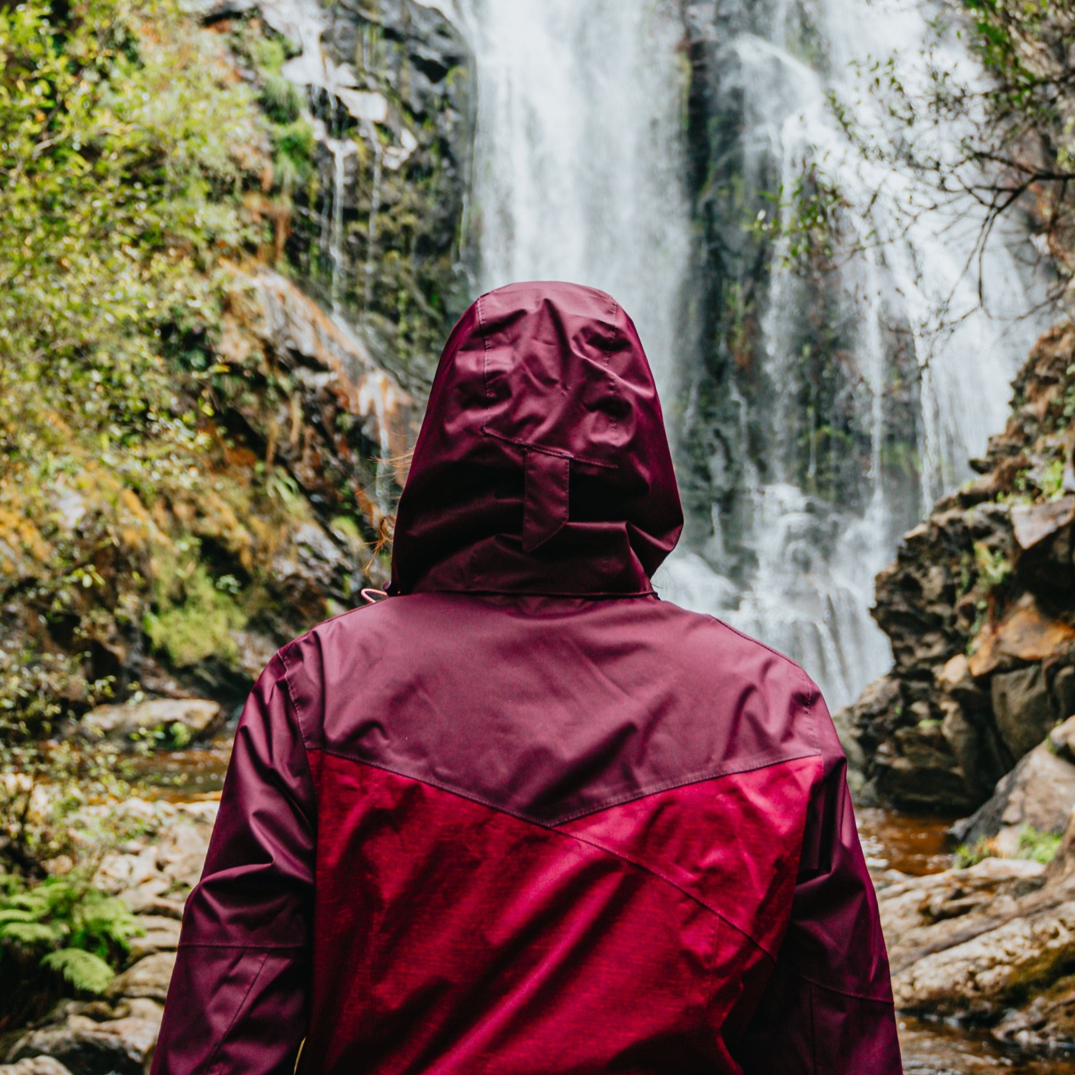 person-in-red-raincoat-admires-a-huge-waterfall.jpg